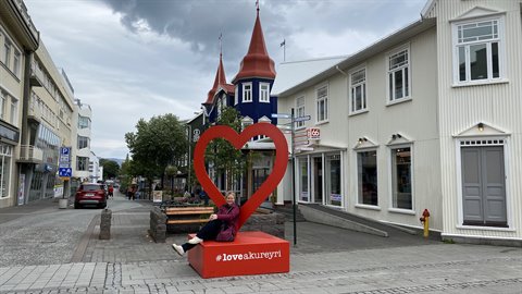 Akureyri, turista appoggiata al cuore rosso nella strada principale