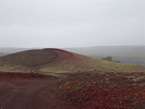 Sentiero rosso di scorie vulcaniche sale sul cratere sotto la nebbia