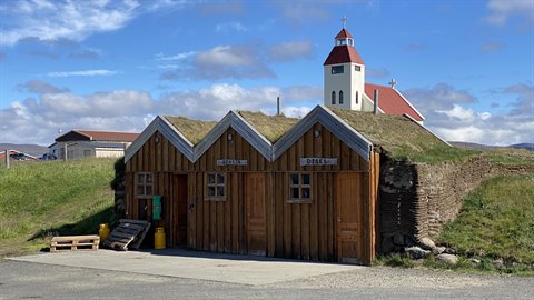 Case in legno con tetti di zolla e chiesa bianca sullo sfondo, Grindavik? Meglio: Dann? Sembra la ci