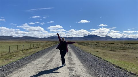 Donna balla con braccia alzate sulla strada sterrata verso Modrudalur