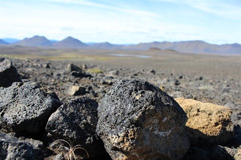 Rocce di lava nera a Mývatn, montagne vulcaniche sullo sfondo