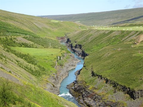 Fiume turchese scorre in una gola verde sotto colline luzide