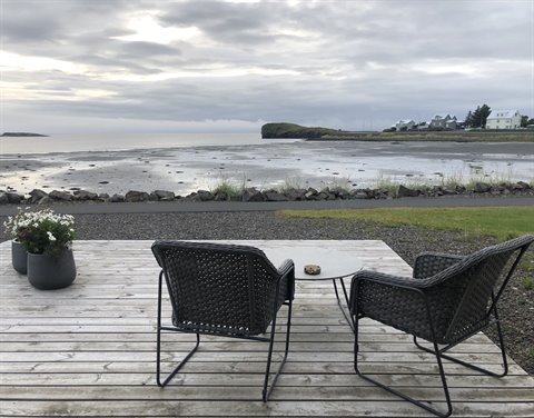 Terrazza in legno con poltrone nere davanti alla baia di Sandgerdi
