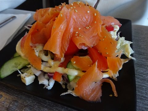 Insalata con salmone affumicato, cetrioli e pomodori su piatto nero