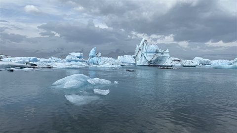 Iceberg azzurri e bianchi galleggiano nelle acque calme di Jokulsarlon, sotto cielo nuvoloso