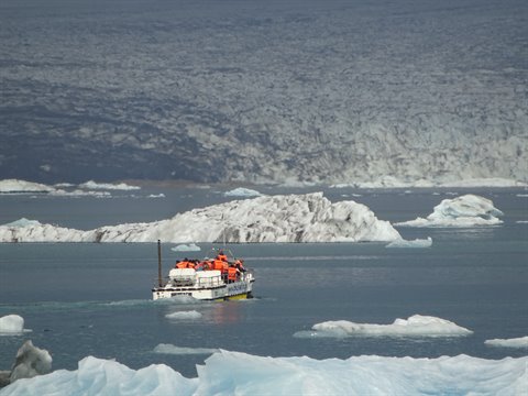 Turista in tuta arancione su anfibio tra gli iceberg di Jokulsarlon