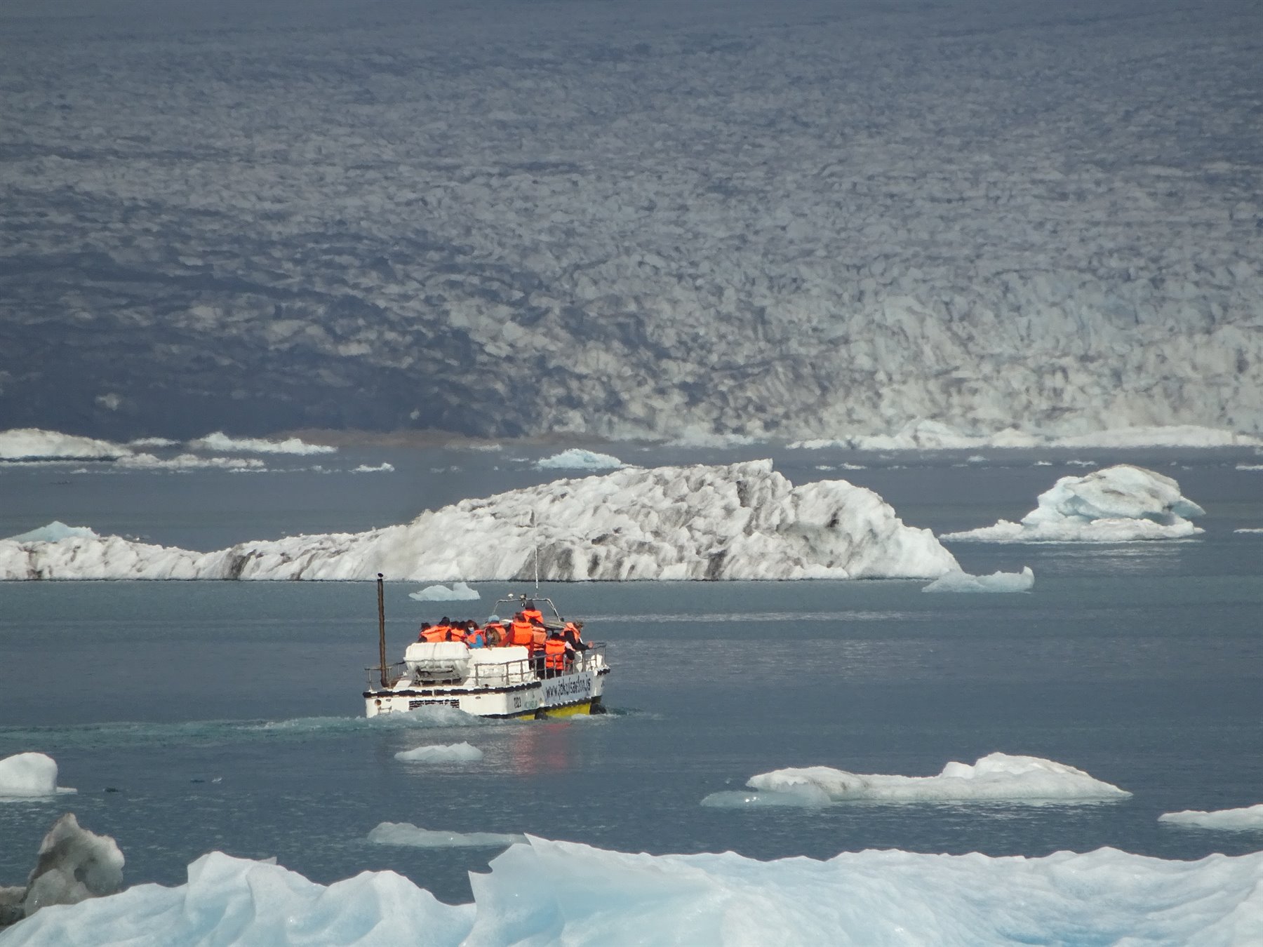 Turista in tuta arancione su anfibio tra gli iceberg di Jokulsarlon