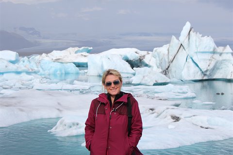 Donna sorridente tra iceberg galleggianti nella laguna di Jokulsarlon