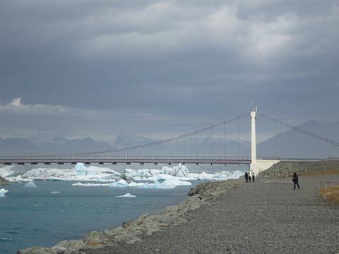 Jokulsarlon: ponte sospeso tra iceberg azzurri, camminatori sulla riva ghiaiosa