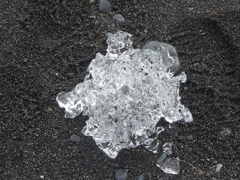 Blocco di ghiaccio trasparente sulla sabbia nera di Jokulsarlon