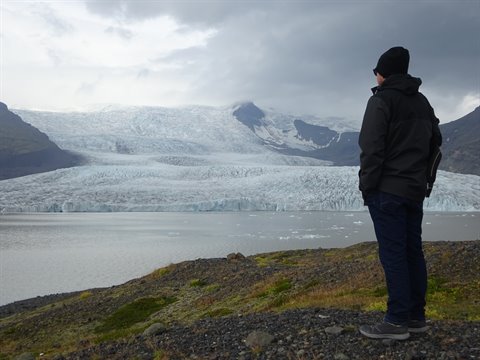 Turista contempla il ghiacciaio Svínafellsjökull sotto un cielo grigio
