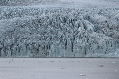 Fronte glaciale striato di blu e ghiaccio nero sull'acqua stagnante