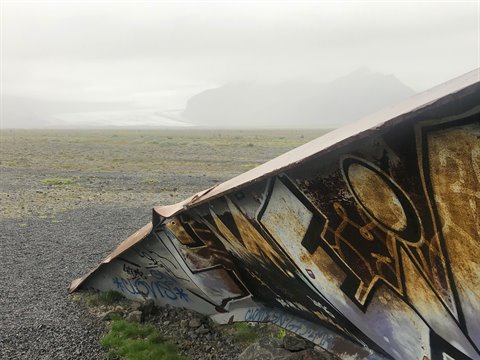 Relitto di metallo graffiti sulla ghiaia, nebbia sul ghiacciaio, vicino a Vík