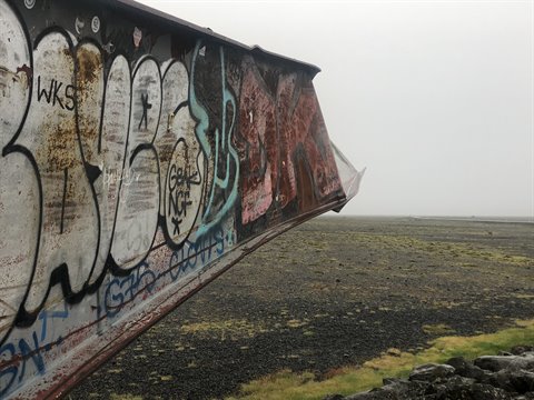 Trave di metallo arrugginito coperta di graffiti sulla spiaggia di Sandgerdi