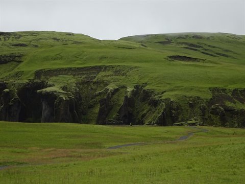 Colline verde brillante sotto cielo grigio, sentiero tra i prati, vicino Vik