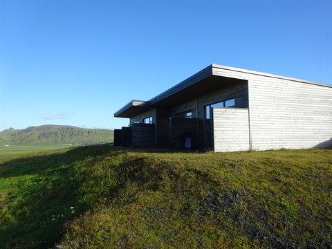 Casa in legno sulla collina erbosa sotto il cielo azzurro