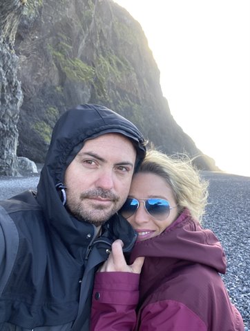Selfie di coppia sulla spiaggia di sassi neri di Vík, vento forte