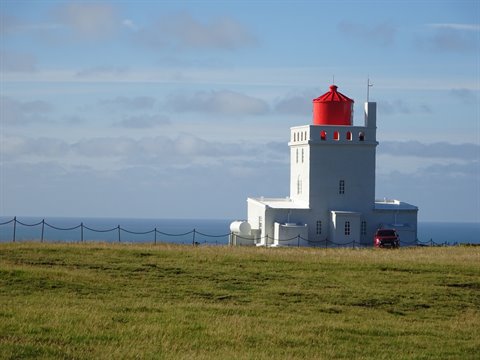 Il faro bianco con lanterna rossa di Dyrhólaey sopra l'oceano