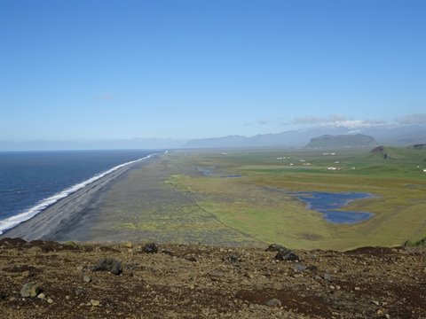 Costa nera con spiaggia sabbiosa, paludi verdi e montagne a Dyrhólaey