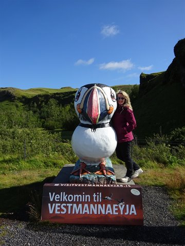 Turista accanto alla statua gigante del pulcinella di mare, Vestmannaeyjar