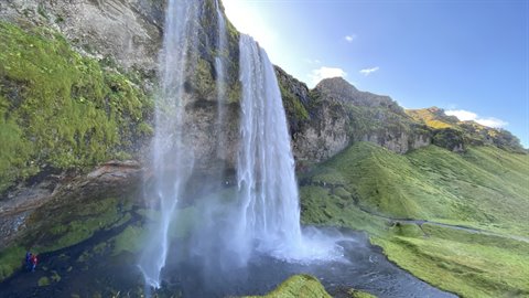 Seljalandsfoss, cascata tra muschio verde e rocce sotto il cielo azzurro