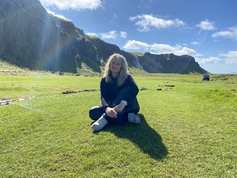 Sorridente sull'erba davanti alla cascata di Seljalandsfoss, vicino a Vík