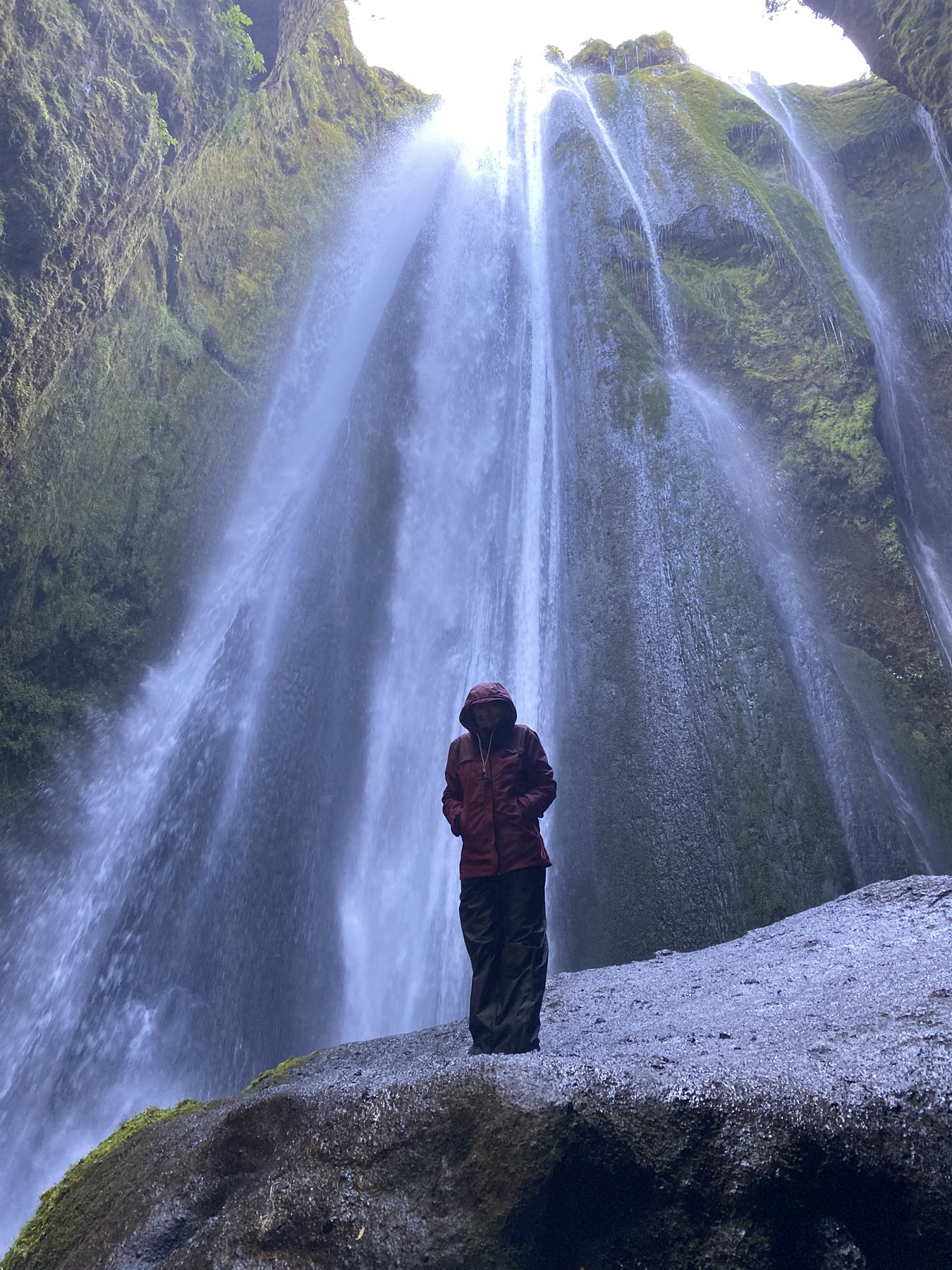 Donna con giacca rossa sotto le cascate di Gljúfrabúi
