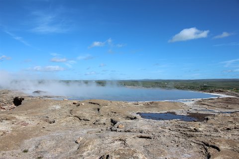 La piscina termale fumante del Great Geysir circondata da roccia vulcanica