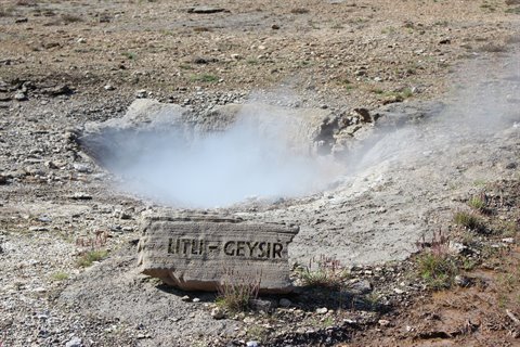 Lítli-Geysir: pietra incisa davanti alla sorgente fumante tra terra vulcanica sterile