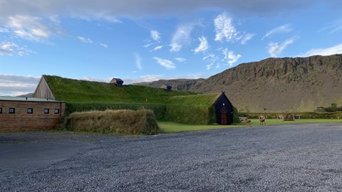 Casa in zolle erbose a Eiriksstadir, montagne e cielo nuvoloso