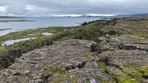 Þingvellir: crepa lavica muschiosa sopra il lago sotto cielo grigio