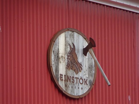 Insegna vichinga di legno con ascia conficcata sul muro rosso di Einstök
