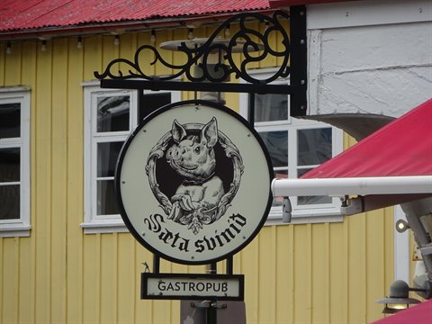 Insegna in ferro battuto del Sæta svíð gastropub su facciata gialla a Reykjavik