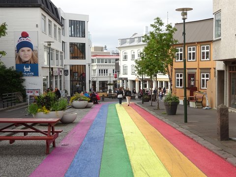 Via arcobaleno a Reykjavik, pedoni tra case colorate sotto cielo grigio