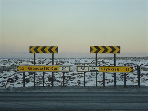 Yellow road signs on snowy ground under grey sky, Iceland