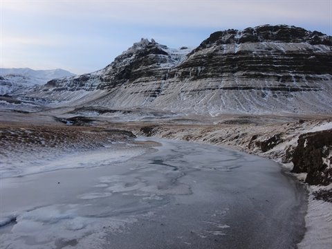 Frozen river winding through snowy mountains, cold morning light, travel journal page