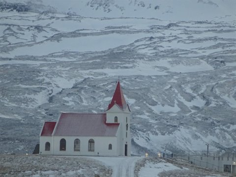 White church with red roof among snowy hills, cold diffuse light