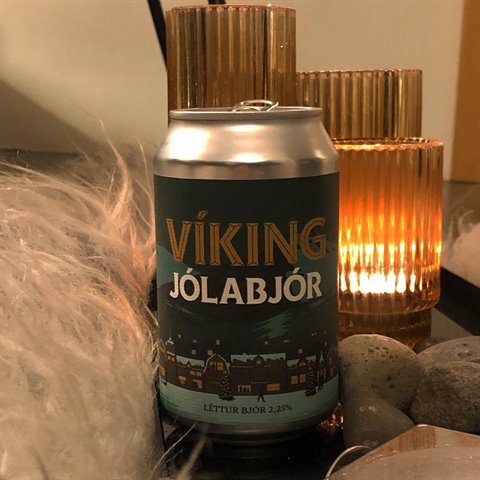 Viking Jólabjór beer can on a table, next to lit candles and stones