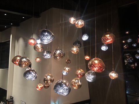 Metallic spherical pendant lamps glowing inside a modern atrium