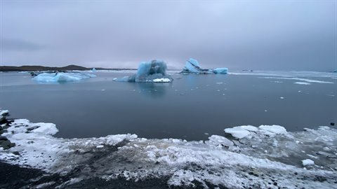 Open travel journal on blue floating icebergs in glacial lagoon, diffuse grey light