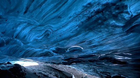 Inside a blue ice cave, cold light entering through the opening, traveler exploring