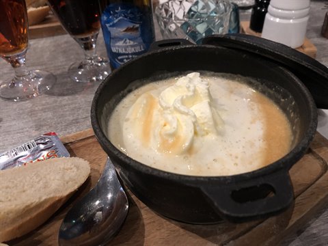 fish soup with bread in cast iron pot on restaurant table