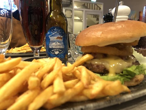 Burger with fries and beer bottle on a restaurant table