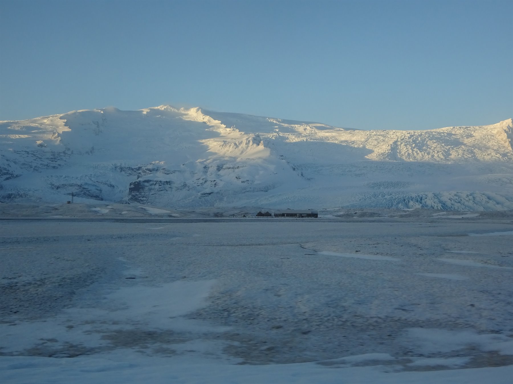 Snowy mountains over frozen plain, warm morning light, film photo from travel journal