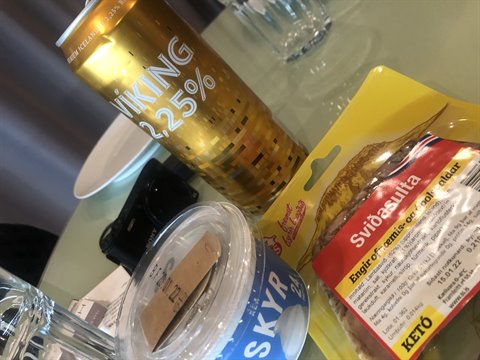 Golden Viking beer can, skyr tub and dried fish snack on glass table