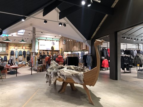 Wooden boat with fur pelts in the middle of a lit clothing store