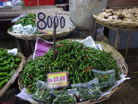 Wicker baskets of green chilies and ginger at market, natural light