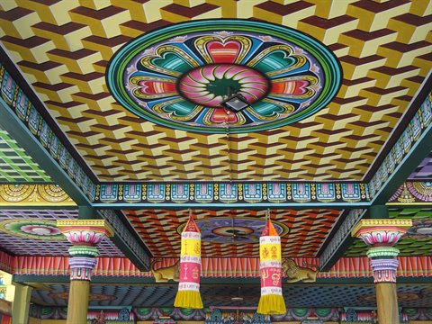 Painted ceiling decorated with geometric and floral patterns, hanging banners between colorful columns
