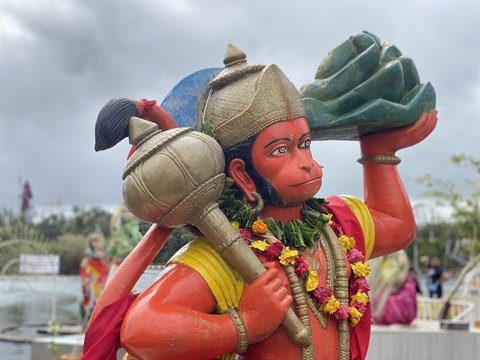Colorful statue of monkey deity holding mace and mountain, diffused light, cloudy sky