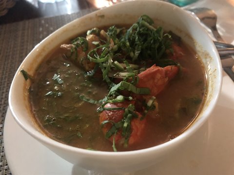 Tomato soup with fresh herbs in white bowl on restaurant table
